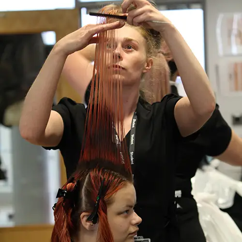 Hairdressing student cutting hair