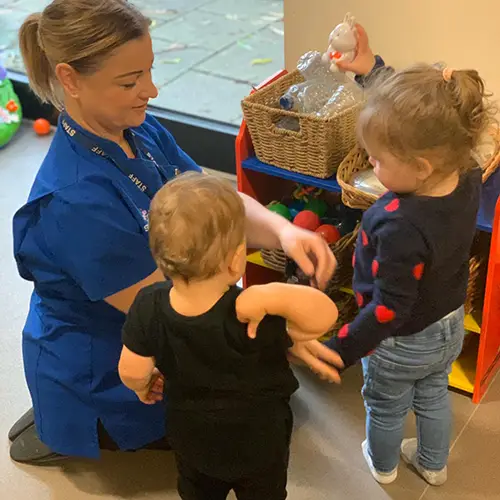 Starting point nursery girls and teacher playing with toys